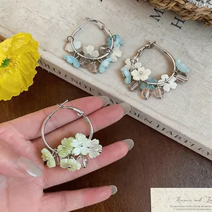Detail of vacation style hoop earrings with delicate resin flower charms