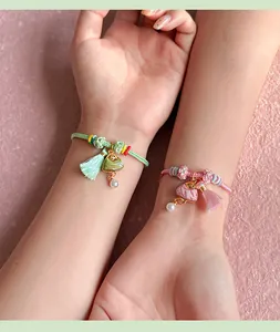 Detail view of handmade Songbrocade triangular charms on colorful rope braided bracelets.