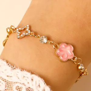 Vue détaillée d'un bracelet en chaîne dorée avec une fleur rose et un pendentif étoile en strass