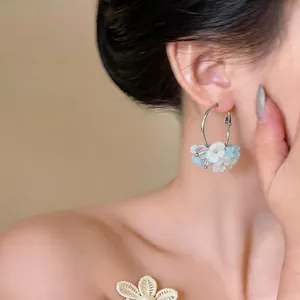 Close-up of sweet resin flower hoop earrings worn on ear, silver needle finish.