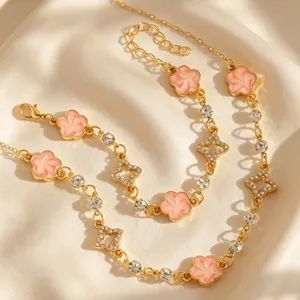 Vue détaillée macro des breloques fleurs roses et étoiles sur ensemble de bijoux dorés