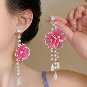 Close-up of pink mesh flower and pearl drop earrings worn on ear with teardrop pendant