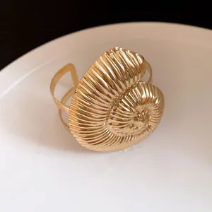 Vue rapprochée d'un bracelet jonc ouvert en forme de coquillage doré avec finition texturée.