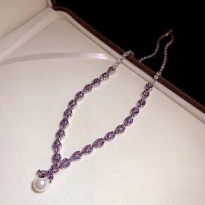Elegant silver-toned necklace featuring purple zircons and a white pearl pendant.