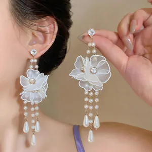 Detail view of oversized mesh flower and pearl drop earrings on a model