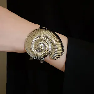 Gros plan d'un bracelet manchette métallique en forme de nautile argenté au poignet