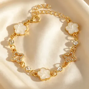 Gros plan d'un bracelet doré orné de trèfles blancs et de cristaux en forme d'étoiles