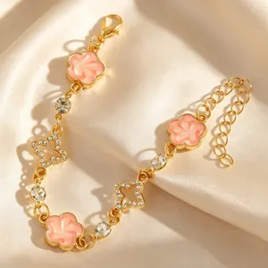 Zoom sur un bracelet doré orné de breloques fleurs roses et de motifs étoiles scintillants