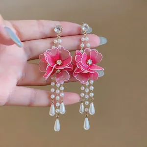 Close-up detail of handcrafted pink mesh flowers and hanging pearls on elegant earrings
