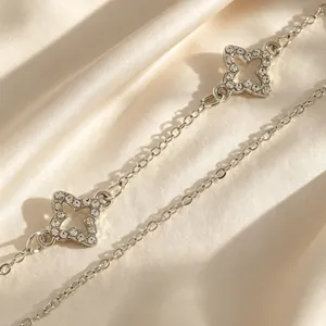 Détail d'un collier trèfle argenté avec des breloques en cristaux étincelantes
