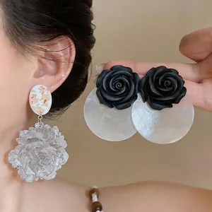 Close-up detail of resin flower earrings and black rose studs with translucent discs