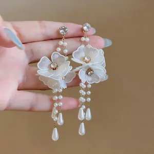 Detailed close-up of elegant white mesh flower earrings with pearls and rhinestones
