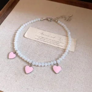 Elegant minimalist beaded anklet with pink enamel heart pendants and adjustable chain link.