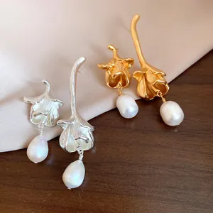 Close-up of matte gold and silver flower earrings with elegant freshwater pearl drops