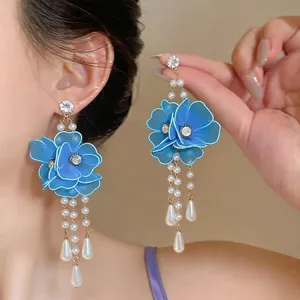 Detailed view of large blue mesh flower earrings with dangling pearls and crystals.