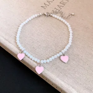 Elegant white beaded anklet featuring three delicate pink heart charms and adjustable chain