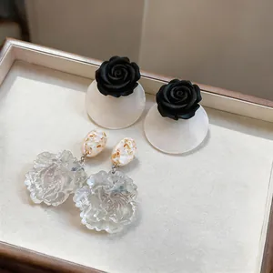 Exquisite close-up of resin rose studs and iridescent translucent flower drop earrings