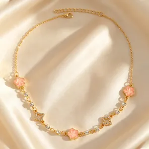 Détail d'un collier en or avec des fleurs roses et des diamants sur fond de soie