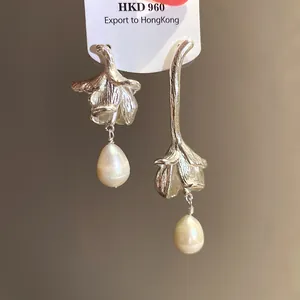 Close-up detail of vintage silver flower earrings featuring asymmetric dangling freshwater pearls
