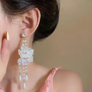 Close-up of elegant silk mesh flower and pearl tassel drop earrings on model