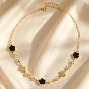 Gros plan détaillé d'un collier doré avec des trèfles noirs et des éléments étoilés.