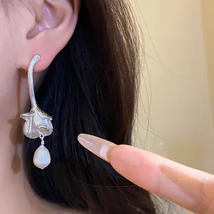 Close-up detail of vintage silver floral drop earrings with a freshwater pearl charm