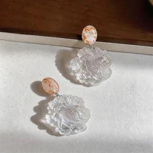 Close-up of resin flower earrings with oval marbled studs for seaside vacation style.