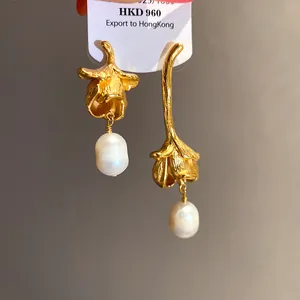 Close-up detail of vintage golden flower earrings with white freshwater pearl drops