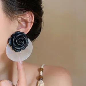Detailed view of a black resin rose earring with translucent acrylic backing