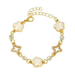 Vue détaillée des breloques étoile et fleur blanche sur un bracelet mode plaqué or