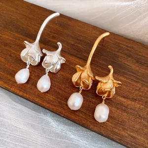 Macro view of vintage gold and silver flower earrings with freshwater pearl drops