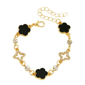 Vue détaillée du bracelet doré avec fleurs en émail noir et breloques étoiles brillantes
