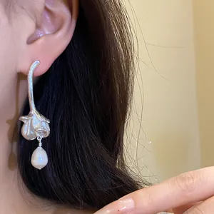 Detail view of a vintage silver flower earring featuring a dangling freshwater pearl drop