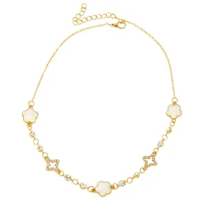 Gros plan du collier doré orné d'étoiles en strass et de trèfles blancs laqués