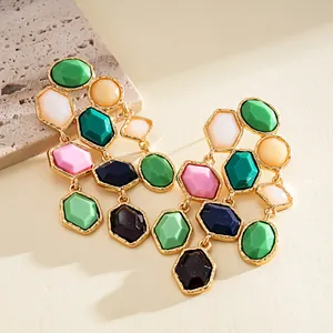 Detailed macro view of colorful geometric resin fringe earrings with gold-toned metal.