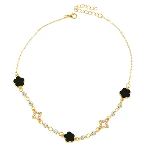 Détail d'un collier doré orné de trèfles en émail noir et d'étoiles scintillantes