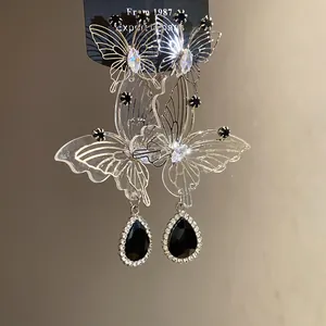Detailansicht der hohlen Schmetterlingsohrringe mit schwarzem Tropfenanhänger und Zirkon.
