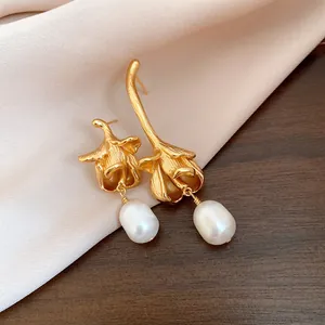 Close-up of elegant vintage floral gold earrings with white freshwater pearl drops