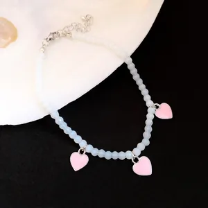 Detail of beaded anklet featuring light blue beads, pink heart charms and adjustable chain