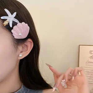 Detail shot of resin starfish and shell hair clips worn on side hair.