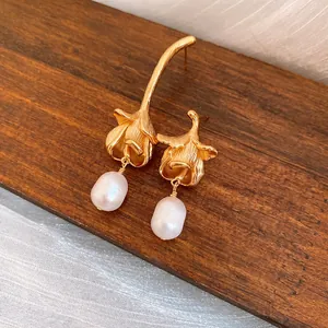 Close-up of vintage flower earrings with freshwater pearl drops on a wooden base