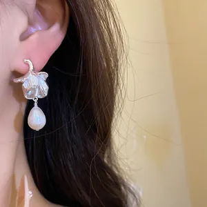 Macro shot of a silver flower stud earring featuring a natural freshwater pearl drop