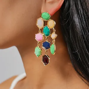 Close-up of vibrant multi-colored geometric resin tassel earrings worn on ear.