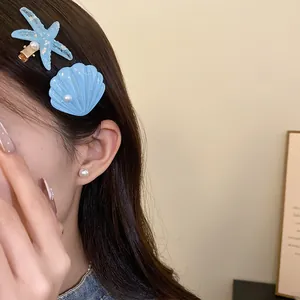 Close-up detail of light blue resin starfish and shell hair clips with white pearls
