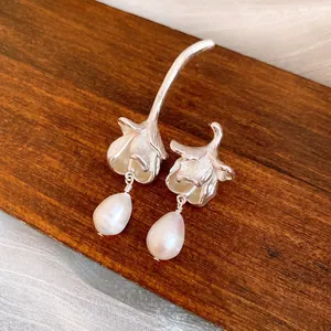 Macro view highlighting the brushed silver texture and iridescent freshwater pearl detail.