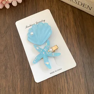 Detail view of blue starfish and shell resin hair clips set with glitter accents