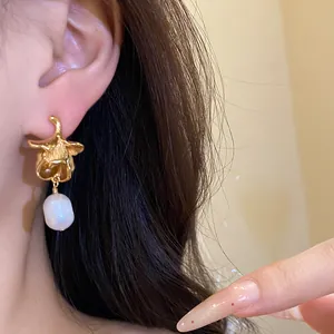 Close-up detail of a vintage gold flower earring with a white freshwater pearl.