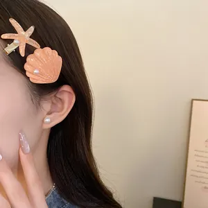 Detailed view of starfish and shell resin hair clips worn by a model, beach style set.