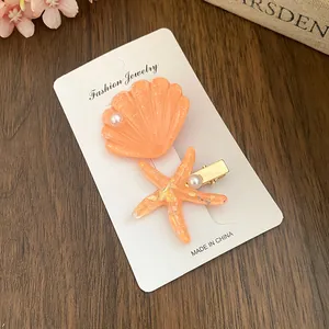 Macro detail view of resin starfish and shell hair clips with pearl accents on display card