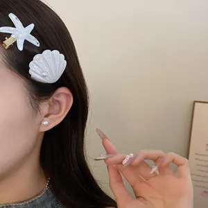 Close-up of white resin starfish and shell hair clips with pearl details on model's hair